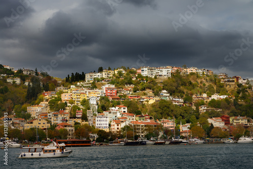 Sun on homes on a hillside of Arnavutkoy Besiktas Istanbul with storm clouds on the Bosphorus Strait photo