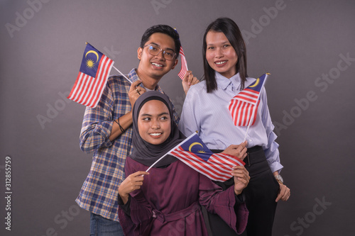 Happy multi racial Malaysian people holding Malaysia Flag.Independence day and patriotic concept.Studio shot.