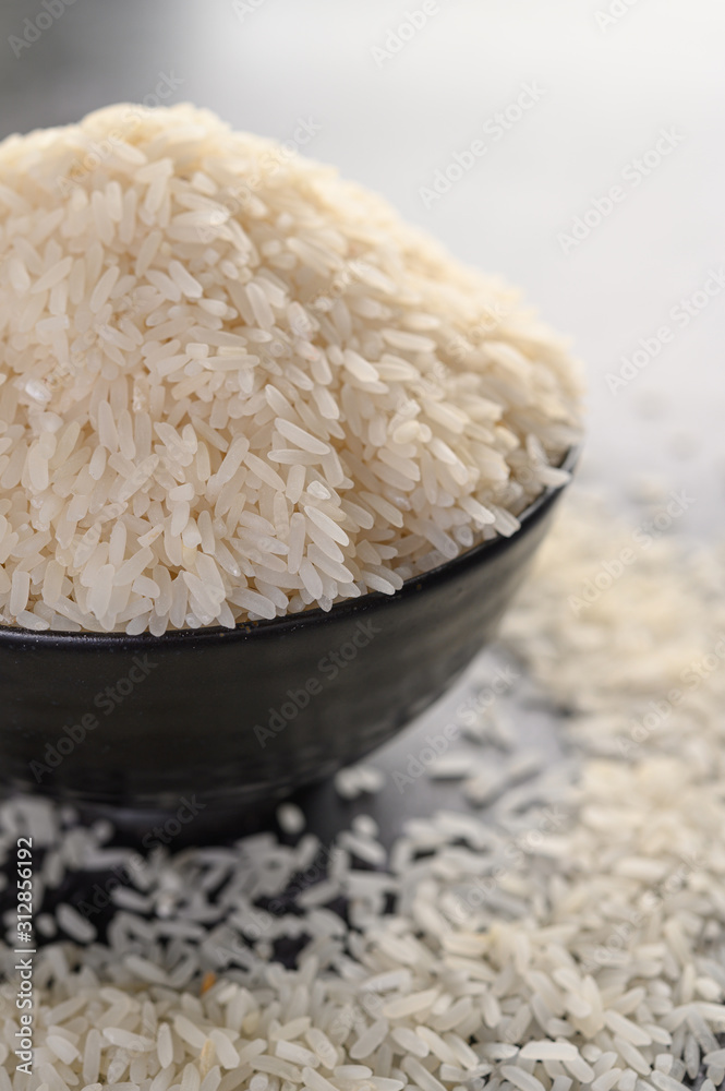 Milled rice in a black bowl on the black cement floor. Milled rice in a black bowl on the black cement floor.