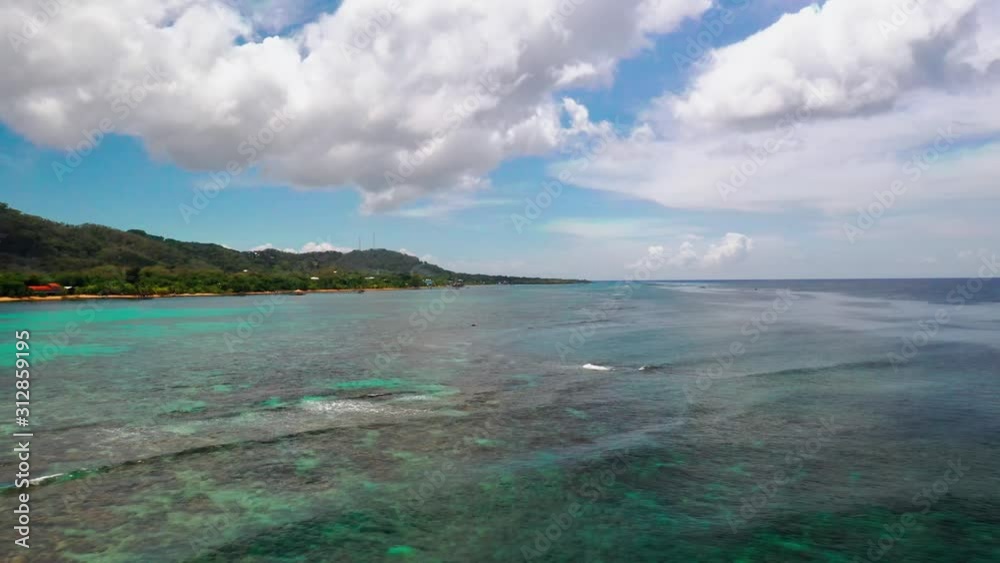 Aerial over shallow turquoise island reef with waves, coastline of Roatan Aerial over shallow turquoise island reef with waves, coastline of Roatan