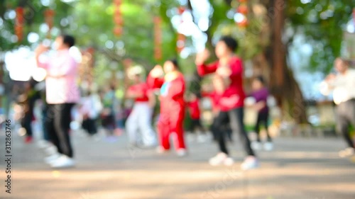 elder Chinese people doing Tai Ji exercise in a park in the morning at blurred focus as background