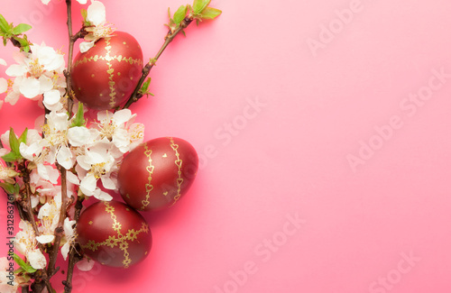 Easter pink background with Easter eggs and spring flowers. Top view with copy space.