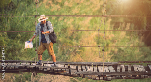 Asian tourist man walking on the old and broken wood bridge