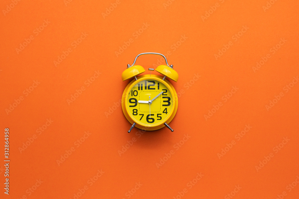 Yellow alarm clock on the middle of orange background - obrazy, fototapety, plakaty 