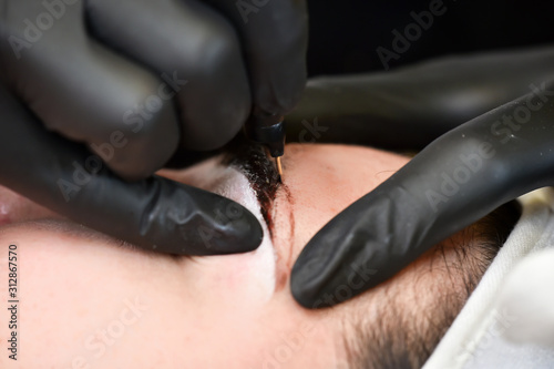 Microblading eyebrows, getting facial care and tattoo at beauty salon photo