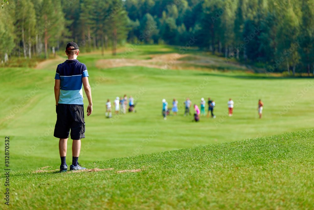 a man standing on a huge green field of golf, amid many other people a man standing on a huge green field of golf, amid many other people