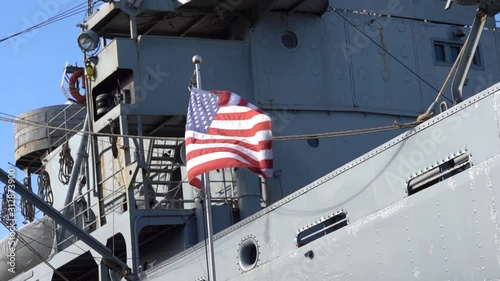 USA flag waving at wind in front of a military ship, slow motion