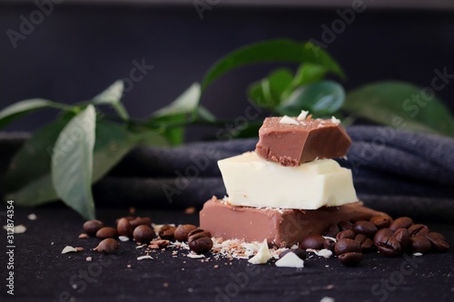 Stacked pieces of milk chocolate and white chocolate bar on black background with coffee beans. photo
