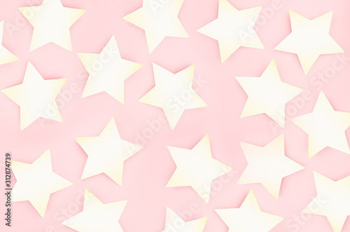 Modern stylish golden festive background - golden stars on soft light pastel pink background as pattern, top view.