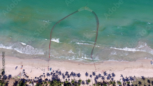 Traditional fishermen in Uppuveli beach, Sri Lanka. They are pulling net from beach. Overfishing make this fishing technique less and less profitable. Nilaveli beach in Trincomalee, Sri Lanka