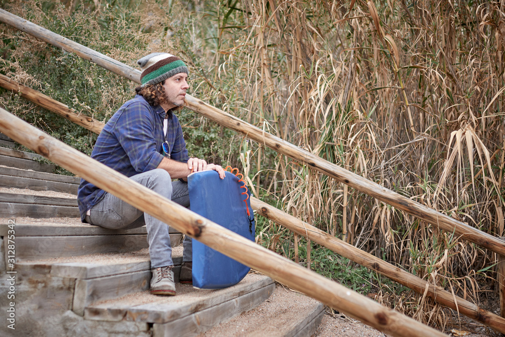a middle-aged man with a surfboard, sitting on some stairs a middle-aged man with a surfboard, sitting on some stairs