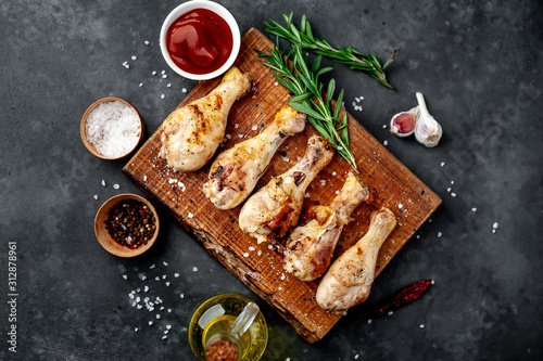 grilled chicken legs with spices on a cutting board on a stone background