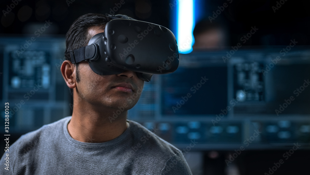 Software Delevoper Wearing Virtual Reality Headset on His Head, Developing  and Programming VR Game or Application. In the Background Technology  Developing Studio with Computers and Monitors Stock Photo | Adobe Stock
