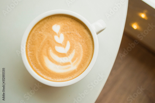 Cup of cappuccino with beautiful latte art on a wooden table in a cafe with copyspace.