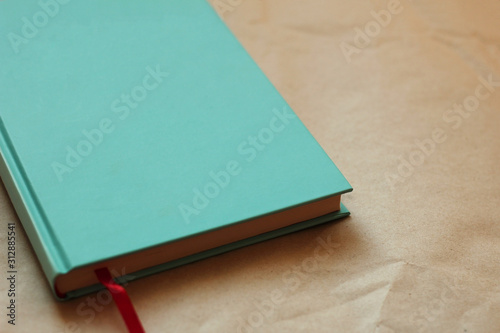 Book cover with blank space for inscription. book with turquoise cover and red bookmark on kraft paper.
