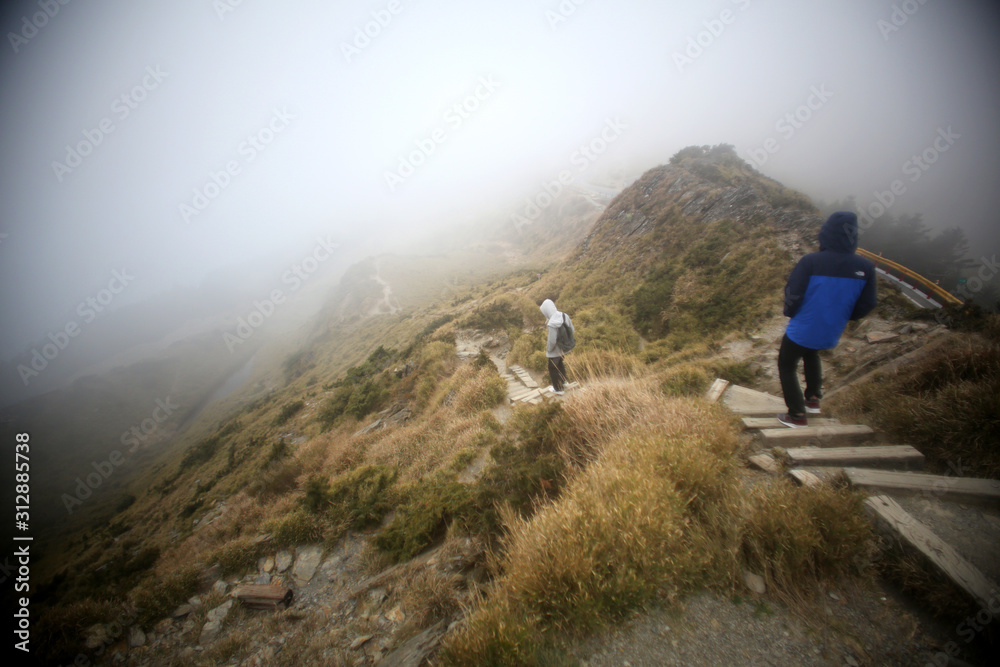 Tourists carefully walk on the misty hiking trail