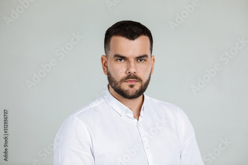 calm handsome bearded man poses in studio on gray background © producer