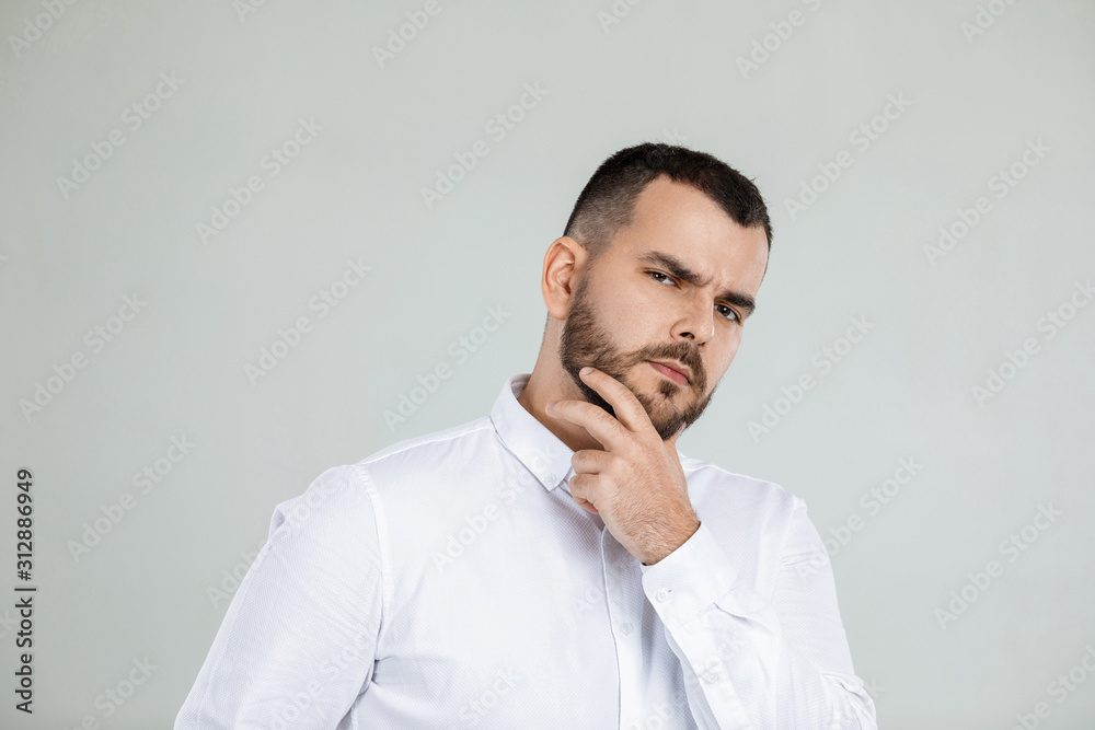 doubtful bearded man thinking about something on gray background. doubtful bearded man thinking about something on gray background.