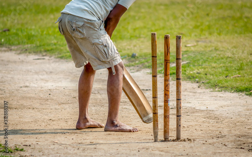A young Indian boy playing cricket. View of a right handed batsman with all three stumps visible.