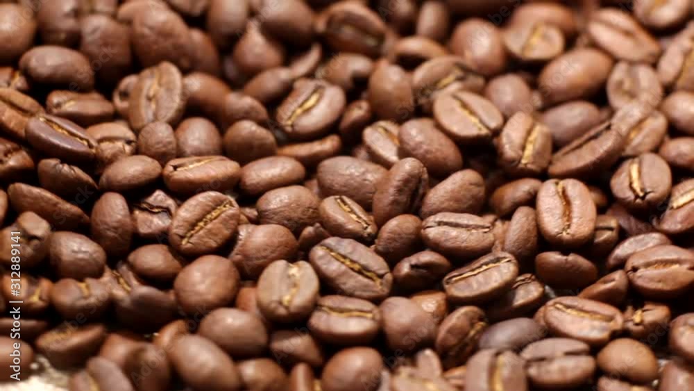 Roasted Arabica coffee beans revolve in a circle, Close-up. Roast of coffee bean. Whole composition scrolls slowly around the camera. Roasted Arabica coffee beans revolve in a circle, Close-up. Roast of coffee bean. Whole composition scrolls slowly around the camera.