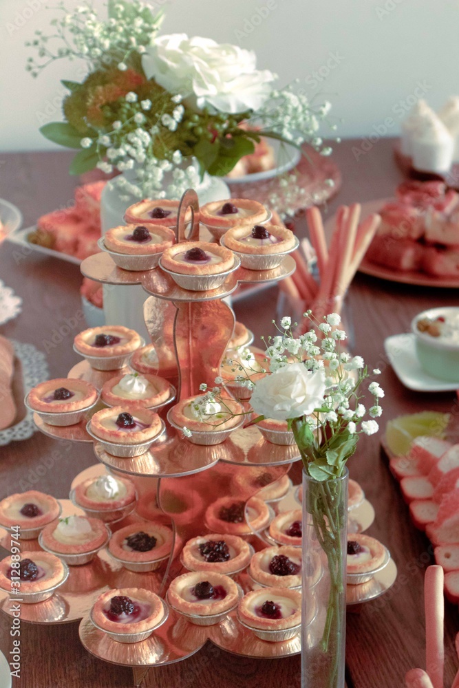 sweet cream pie with jam set on the table like a pyramid with a flowerpot in the background and other foods