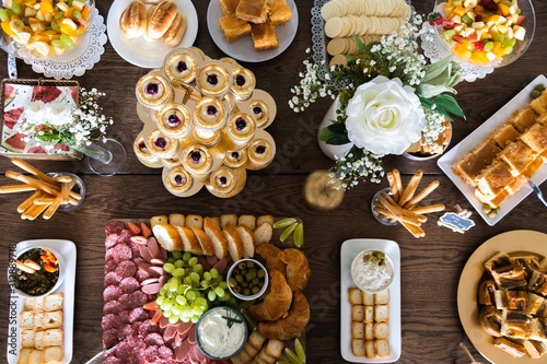 baby food table with snacks, cupcakes, cookies, cream, flowers, banana cake, salami, cheese, croassant