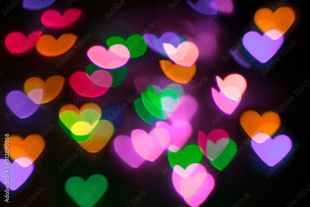 Colorful blurred bokeh hearts on a dark background