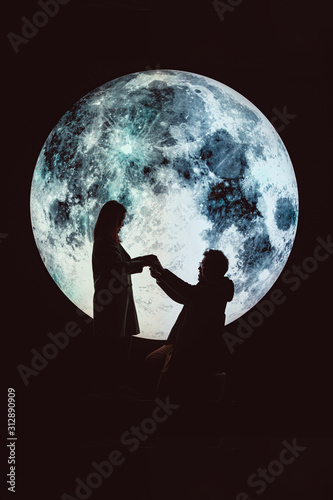 Silhouette picture of man asks a woman to marry on the mountain with A big full moon at night.