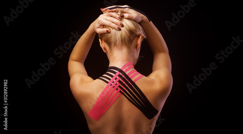 Obraz na plátně Beautiful young woman with kinesiotape on her neck area after injury on black ba