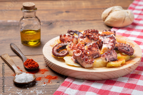Pulpo a la gallega, galician octopus with potatoes, paprika, salt and olive oil.  typical Spanish Galician tapa, on a traditional wooden plate. Tipical Spanish tapa concept. photo