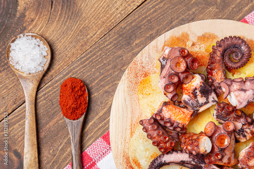 Pulpo a la gallega, galician octopus with potatoes, paprika, salt and olive oil.  typical Spanish Galician tapa, on a traditional wooden plate. Tipical Spanish tapa concept. photo