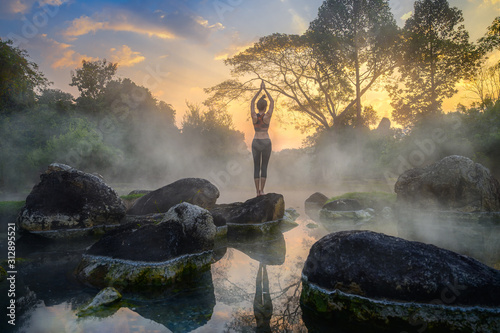 Fotobehang young woman in action of yoga practice in steaming hot spring water, the nature