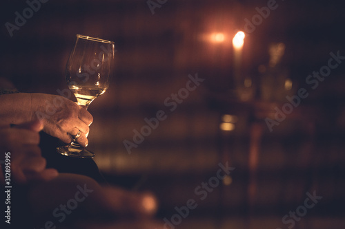 mano femenina sosteniendo una copa de vino con un fodo de velas photo