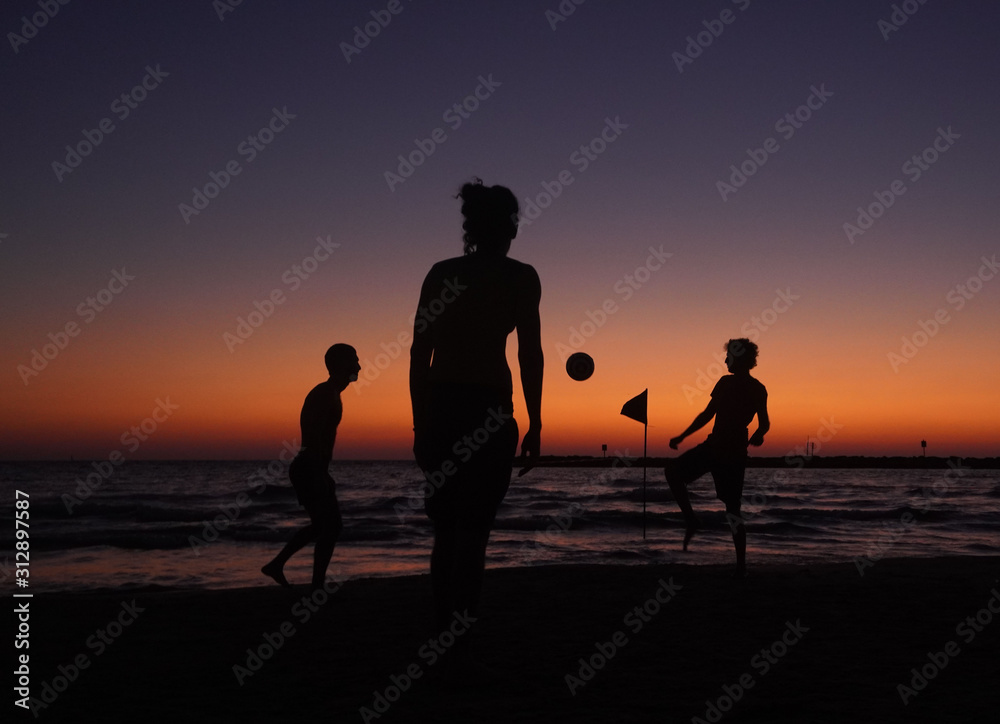 Playing soccer football during the sunset in the beach in front of the sea in Tel Aviv Israel