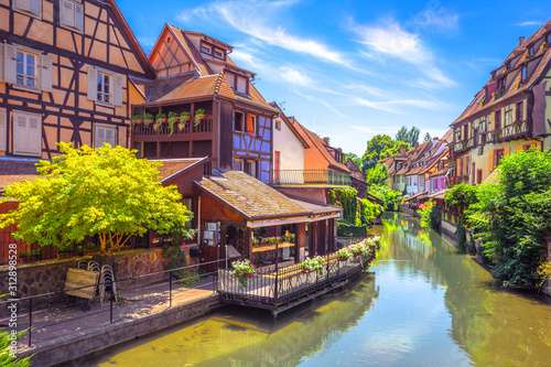 Beautiful view of the historic town of Colmar, also known as Little Venice, with tourists taking a boat ride along traditional colorful houses on idyllic river Lauch in summer, Colmar, Alsace, France