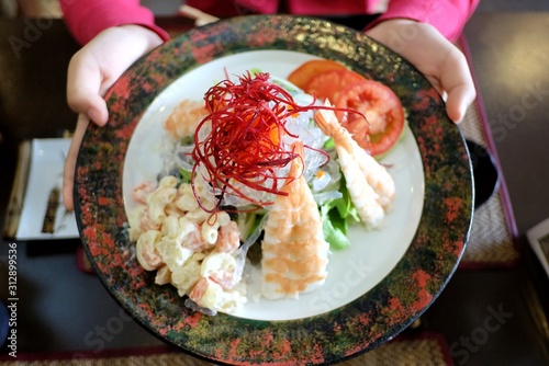 Close op Japanese shrimp salad in a plate on a female holding hands and restaurant area photo