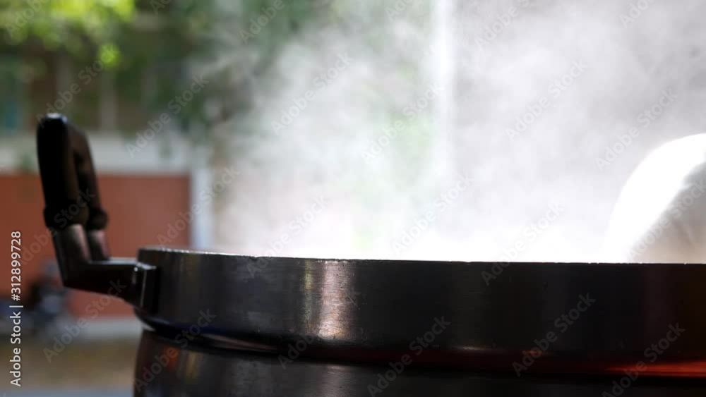 The chef in the restaurant is cooking while using the dipper in a large pot. The water is boiling and the mass of steam reflected in the morning light. The chef in the restaurant is cooking while using the dipper in a large pot. The water is boiling and the mass of steam reflected in the morning light.