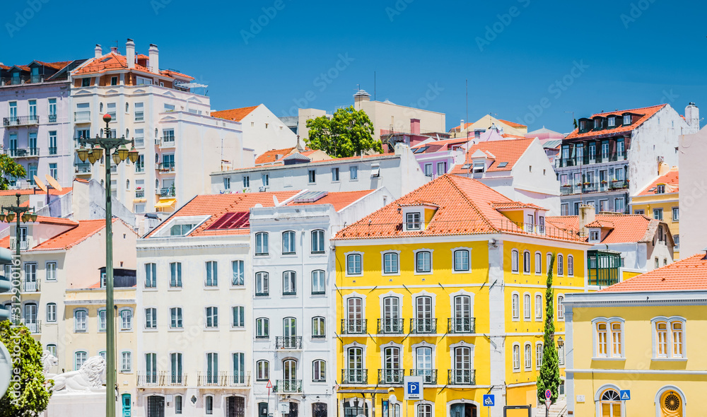 Portugal, Lisbon in summer, street of Lisbon, beautiful yellow house among white houses in Lisbon, forged balconies on the yellow wall, Lion statue in Lisbon