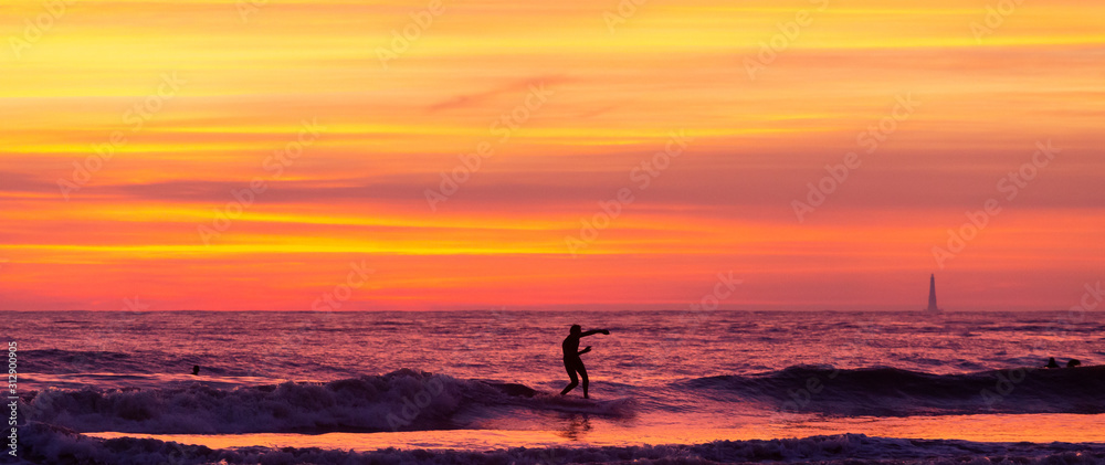 Surfeur au coucher de soleil avec le phare de cordouan 