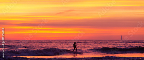 Surfeur au coucher de soleil avec le phare de cordouan 