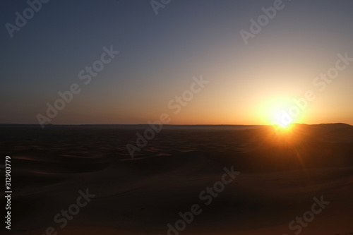 Sun rising over Erg Chebbi dunes Sahara desert at dawn. Morning sunrise time in Merzouga, Morocco.