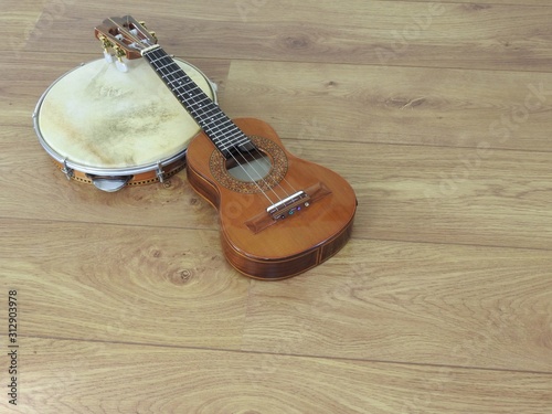 Close-up of two Brazilian musical instruments: cavaquinho and pandeiro (tambourine) on a wooden surface. They are widely used to accompany samba and choro, two popular Brazilian rhythms. Top view. photo