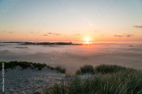 Landscape shot of beautiful sunrise over a foggy valley in the Dunes of Hvide Sand Denmark