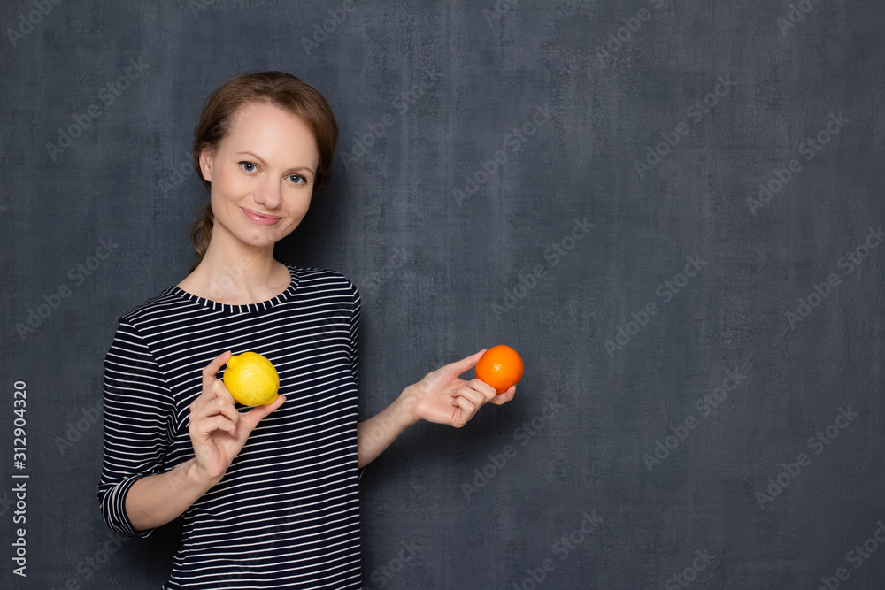 Portrait of happy young woman holding lemon and tangerine in hands Portrait of happy young woman holding lemon and tangerine in hands