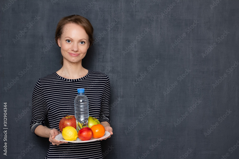 Portrait of happy girl holding dish of fruits and bottle of water Portrait of happy girl holding dish of fruits and bottle of water