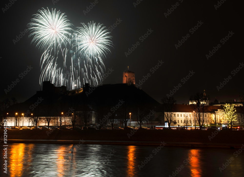 Vilnius, Lithuania - January 01, 2020: Beutifull view to the main firework, at New Year night to Cathedral Square and belfry tower and Cathedral and Gediminas castle with the reflections on the river