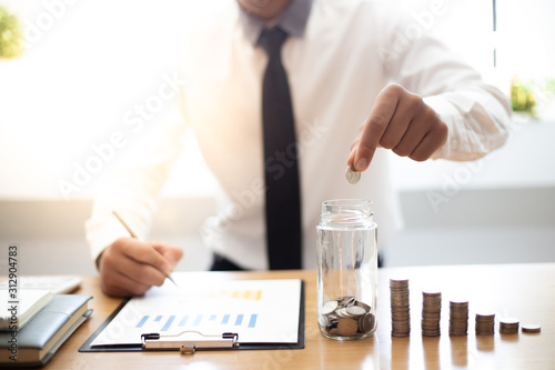Hold a coin in a glass  Businessmen prepare a financial plan by accounting income - expenses for stable business growth saving ideas  Saving money concept