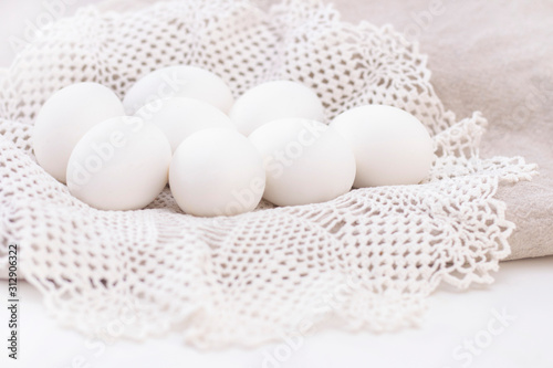 pile of organic white eggs of chicken healthy eating freshness on a brown bag and a white beautiful knitted napkin. for background texture soft focus close-up