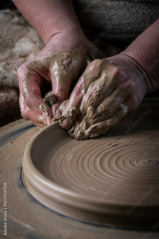 Hand craft making pottery on wheel. Female hands mold ceramic plate from clay