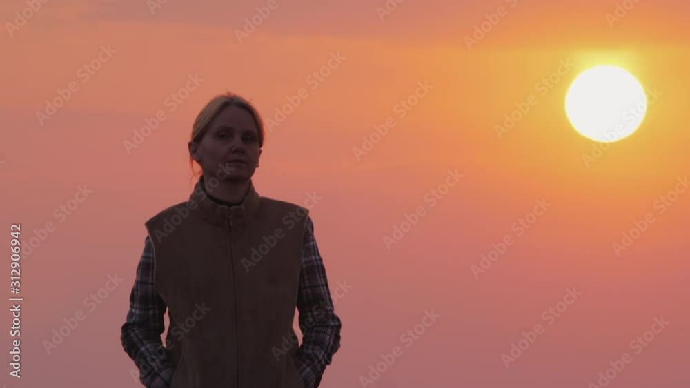 A woman goes forward against the pink sky and the setting sun A woman goes forward against the pink sky and the setting sun